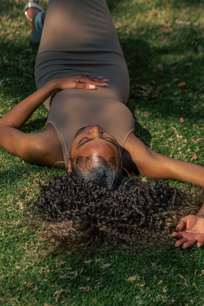 A serene moment of relaxation: an African American woman lies on the grass enjoying a sunny day.